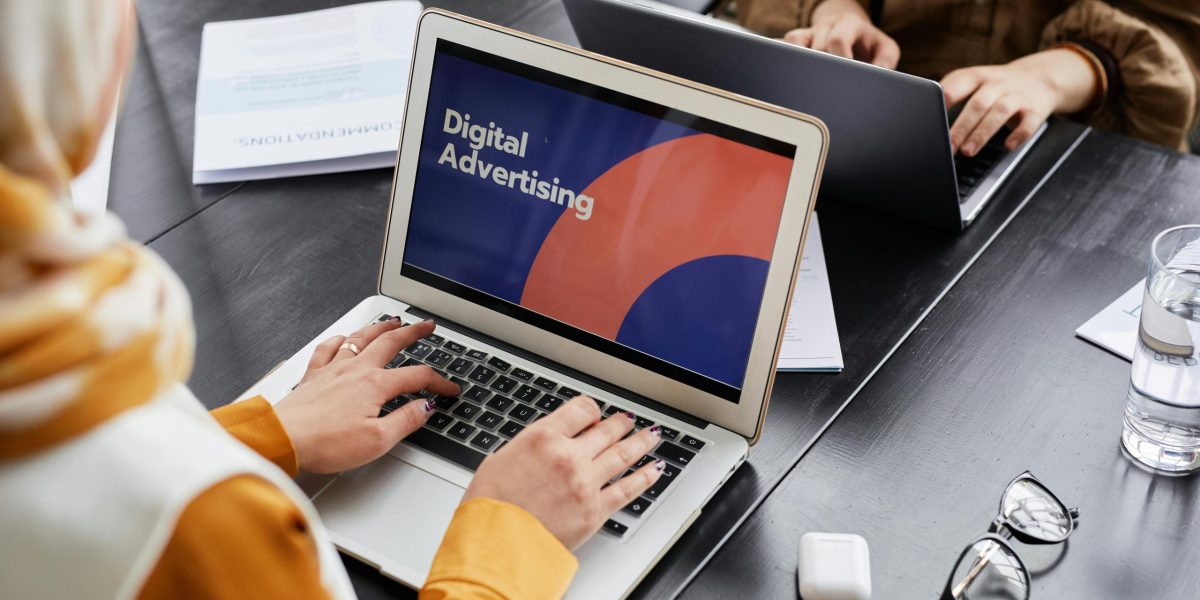 Two professionals work on laptops focusing on digital advertising in an office setting.